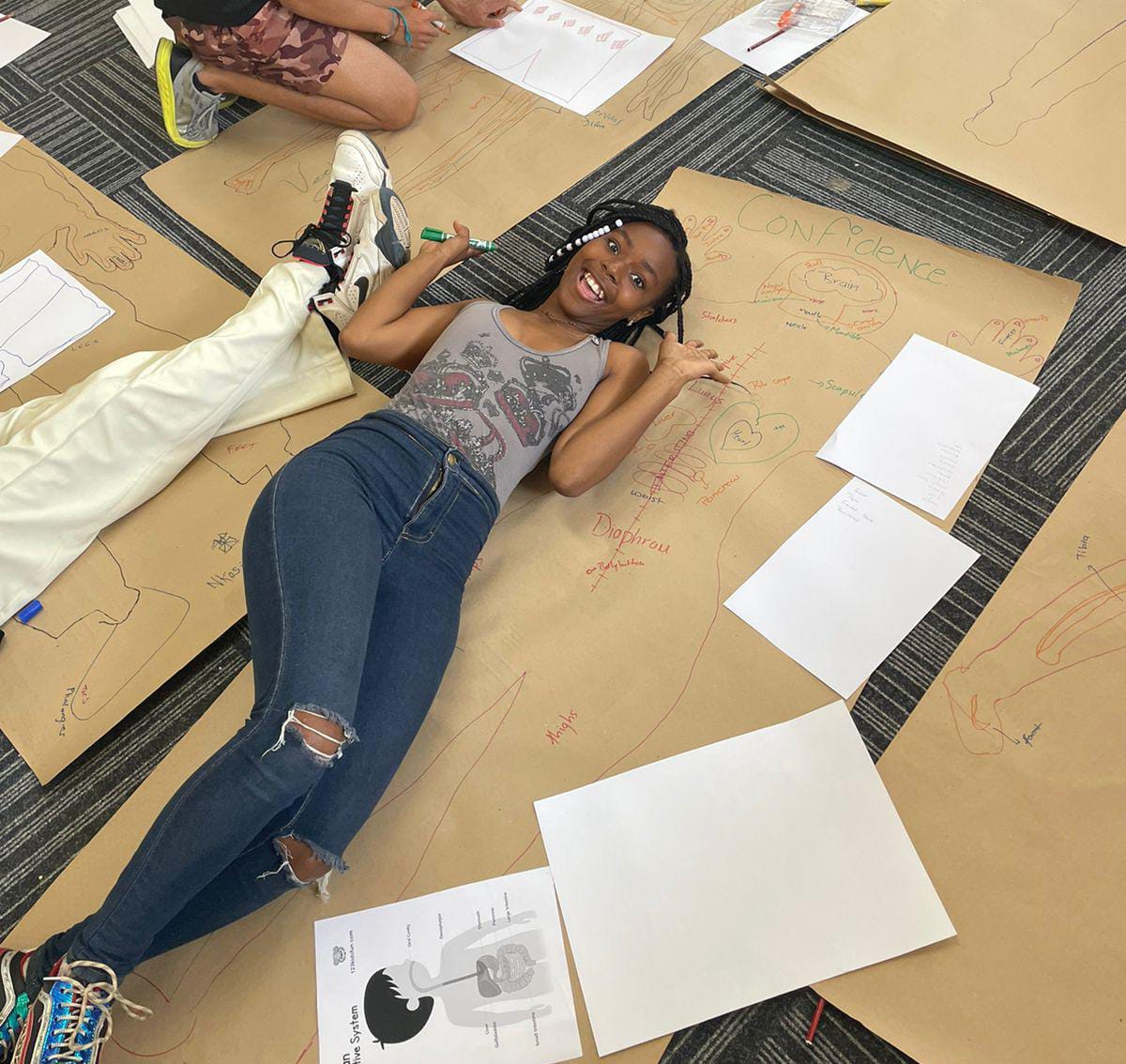 Photo of Thato on the floor next to outline drawing of her body